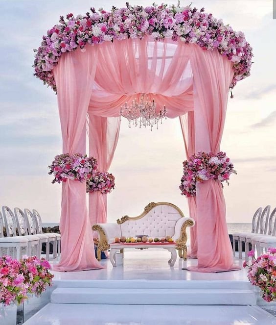 Pink draped mandap with floral crown and crystal chandelier