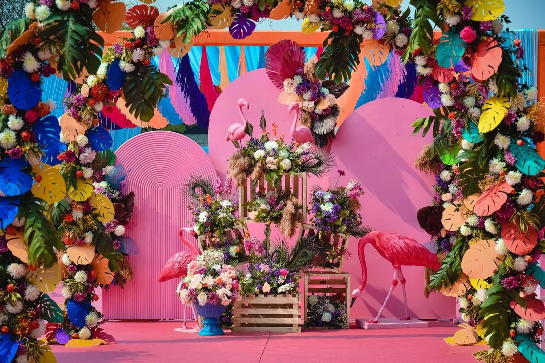 Colorful tropical backdrop with pink flamingos and floral arch