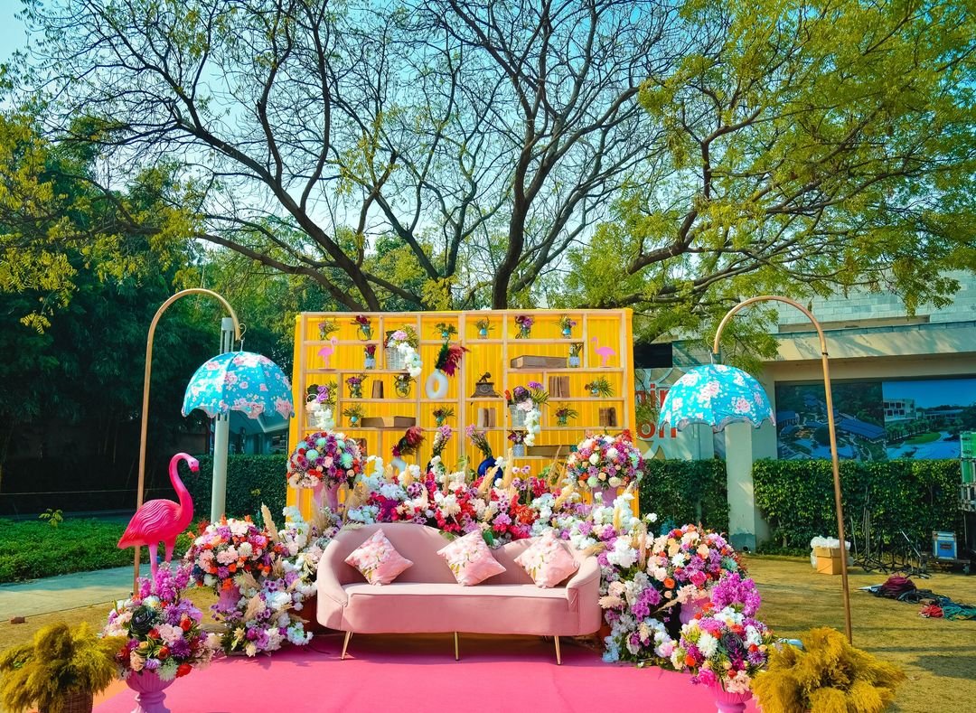 Yellow shelf backdrop with pink sofa and floral styling outdoors