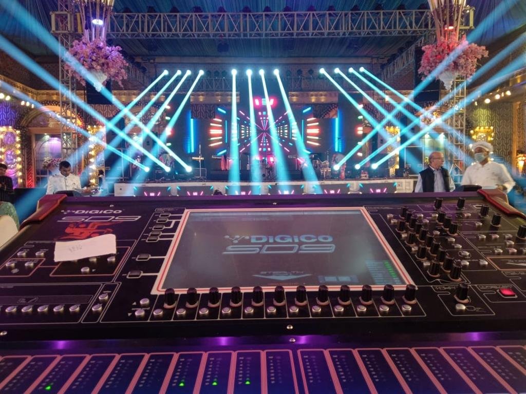 Sound engineer at mixing console with beam lights over stage