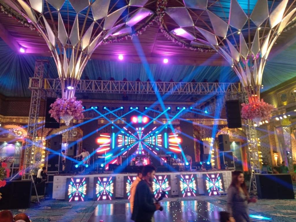 Guests walking past illuminated stage with floral chandeliers