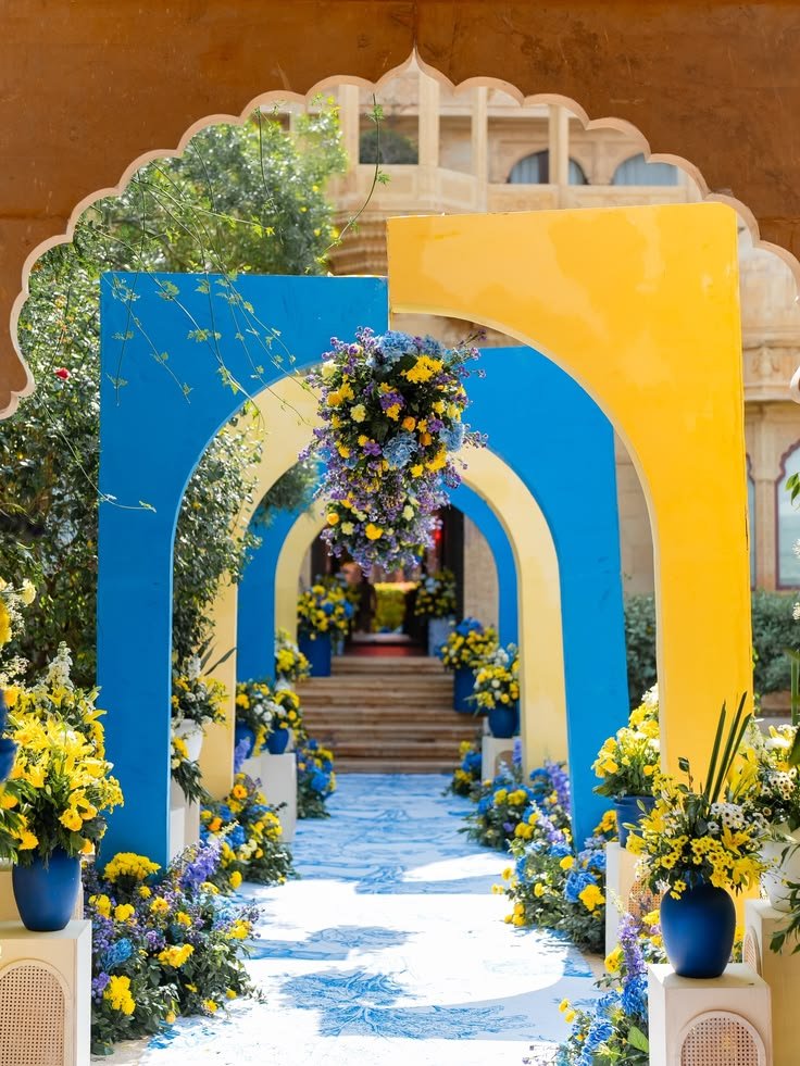 Blue and yellow arch entrance with floral urns at a palace venue