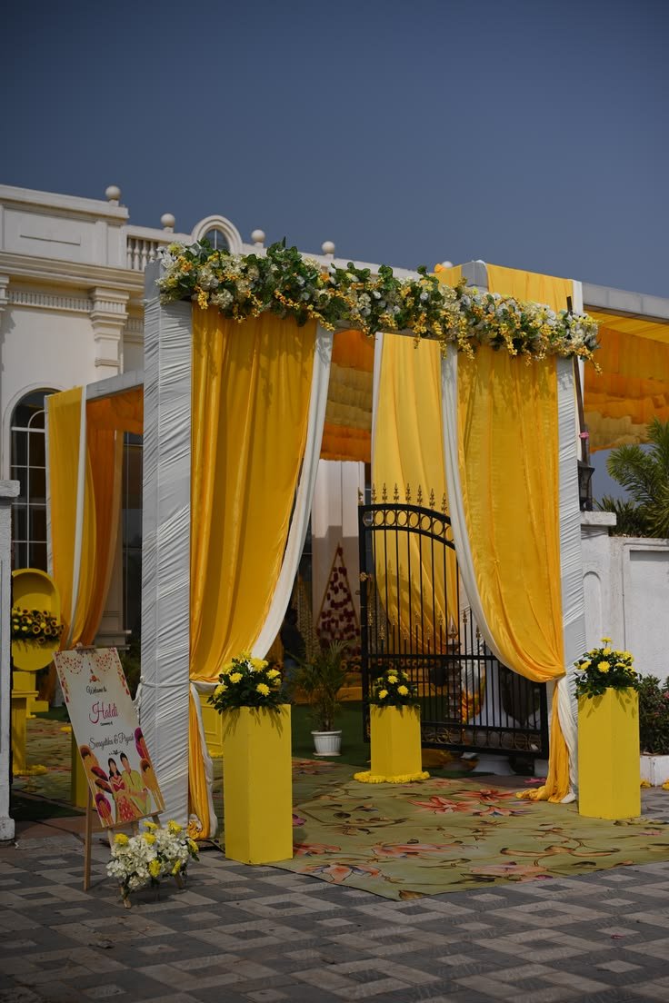 Yellow drape entrance with floral garland and welcome signage