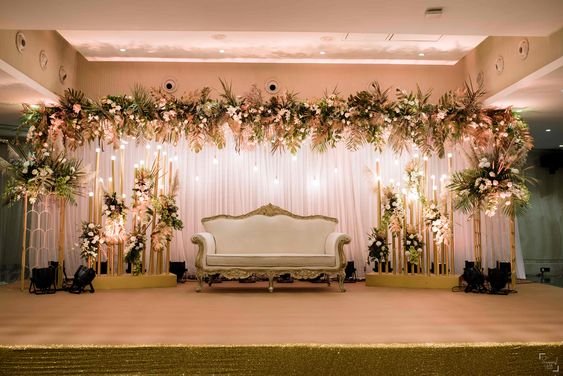 Gold and green floral stage backdrop with white sofa and warm lighting
