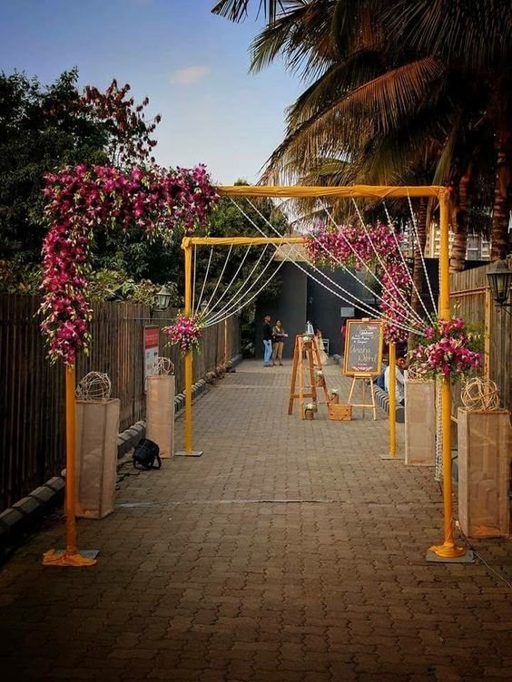 Orange floral arch entrance walkway with fairy lights and palm trees