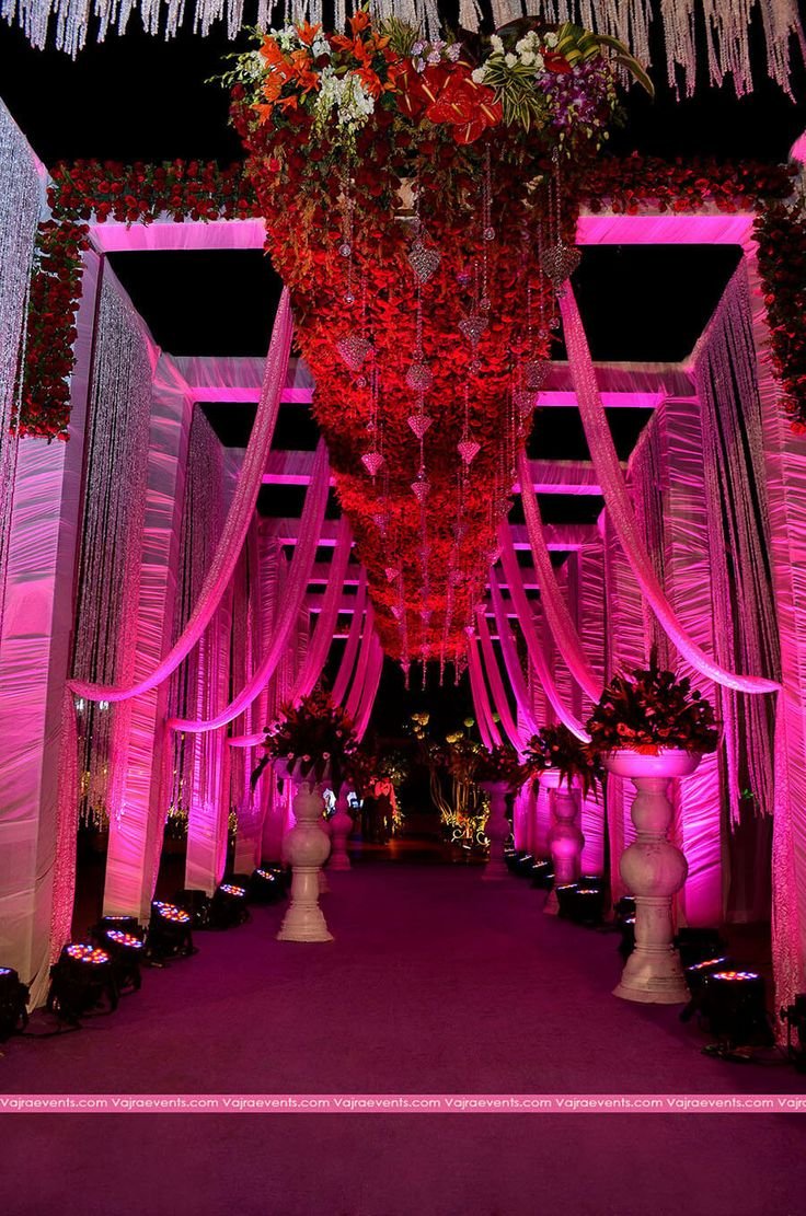 Pink lit corridor with hanging red floral chandelier installation