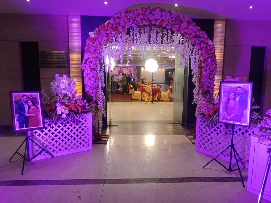 Floral arch entrance to reception lobby with couple portraits on display